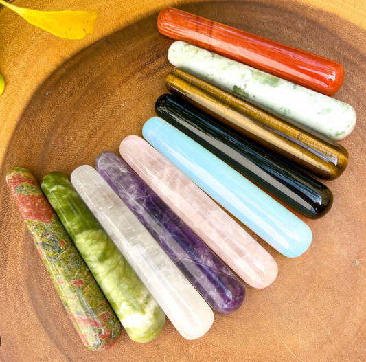 Smooth polished crystal massage wand in assorted gemstones on a dark surface — view 1 of 12