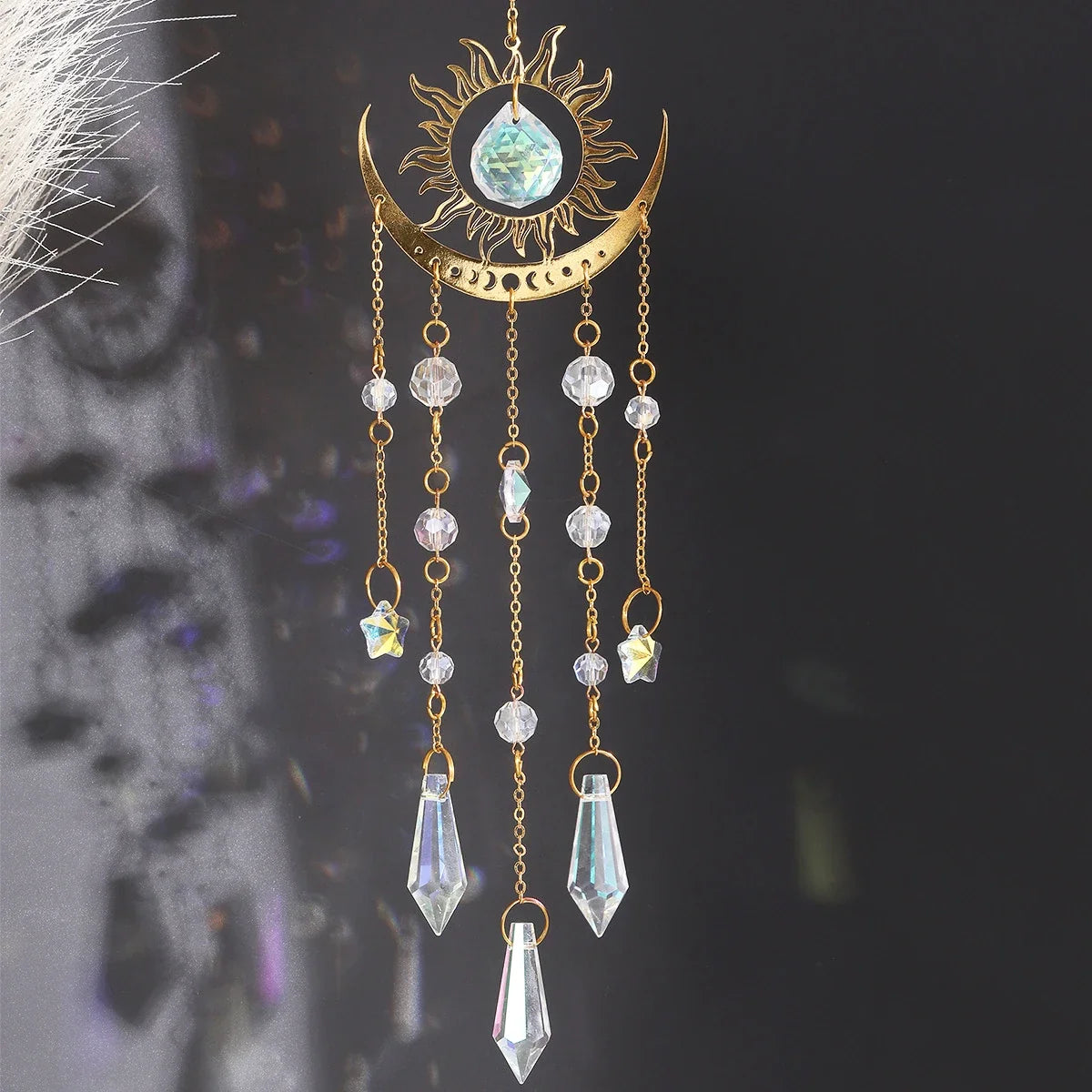 Gold moon phase and sun crystal suncatcher hanging in a window, with faceted K9 crystal prisms
