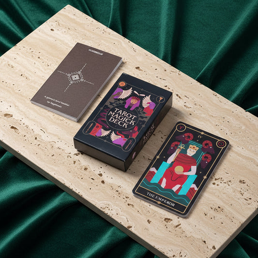 The Tarot Magick Deck box and its guidebook on a travertine slab over green velvet, with The Emperor card standing in front.