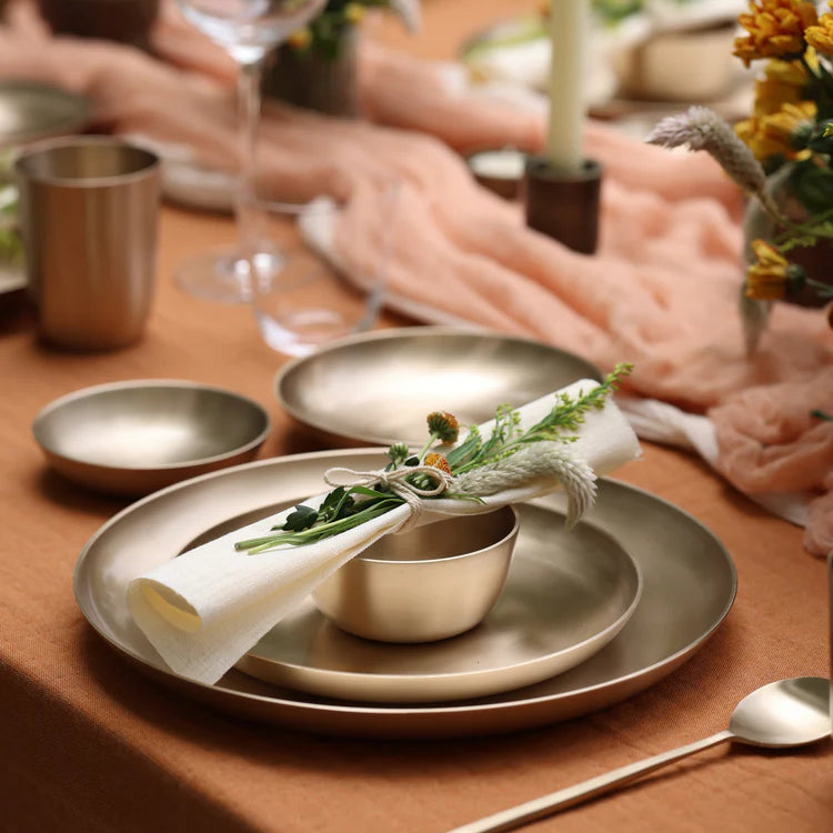 Kansa bronze dinnerware on a laid table with tumbler, bowl and cutlery