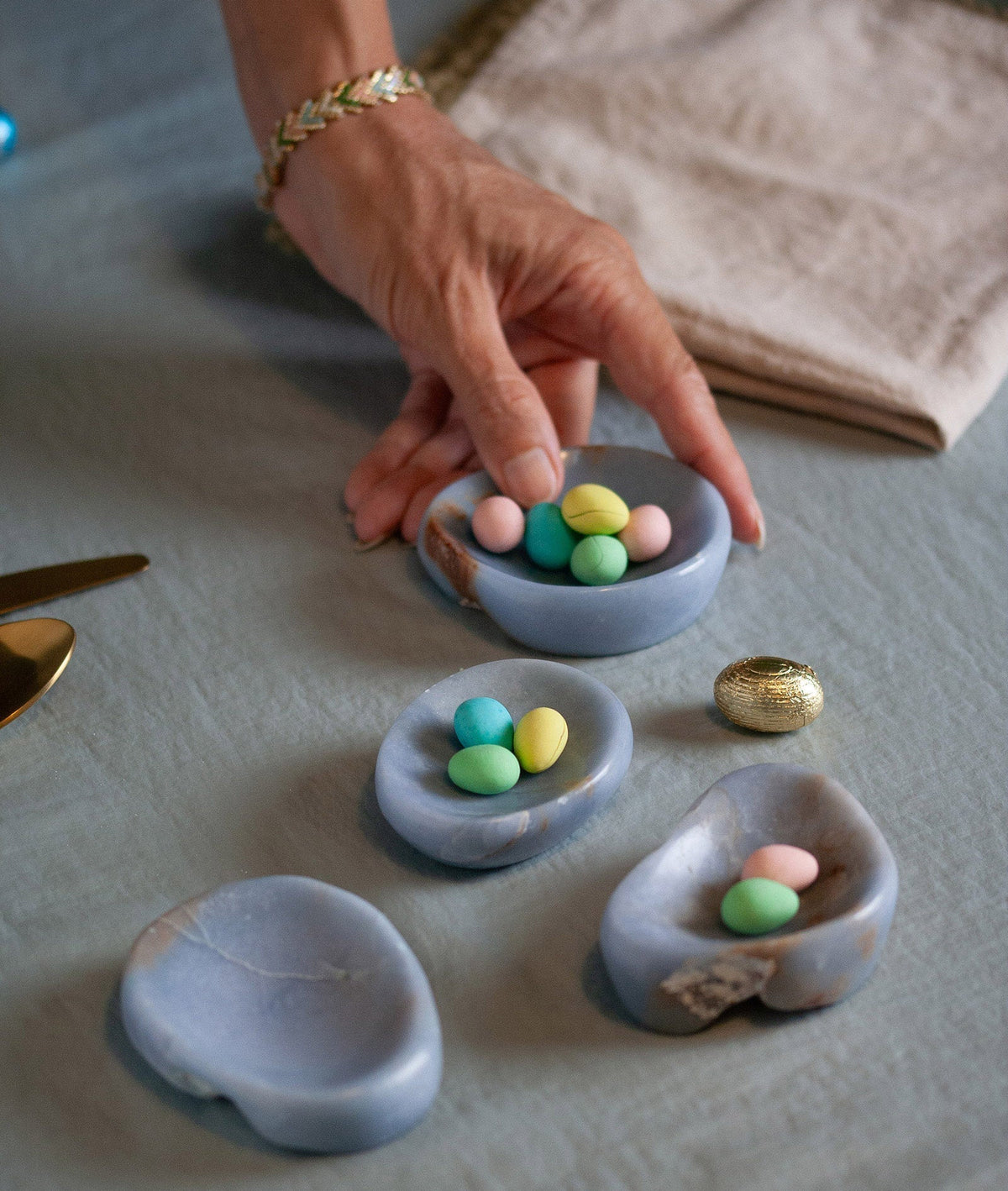Three angelite dishes in different shapes holding sweets on a linen tablecloth