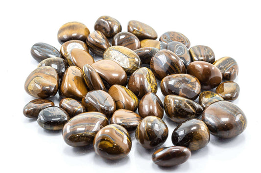 A pile of polished tiger iron tumbled stones showing banded gold, brown and dark grey layers