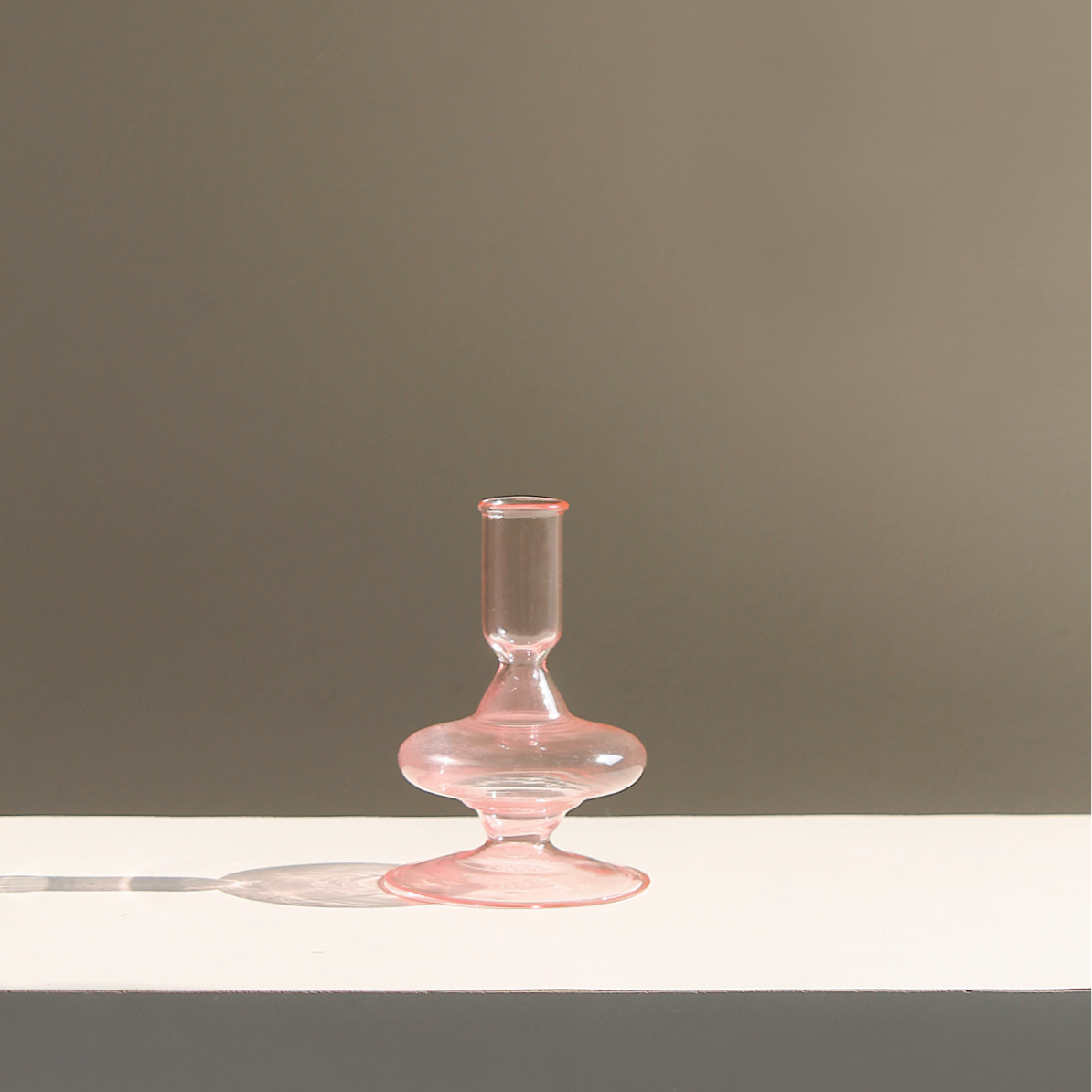Pink Siri glass candle holder in the slimmer profile, casting a soft shadow