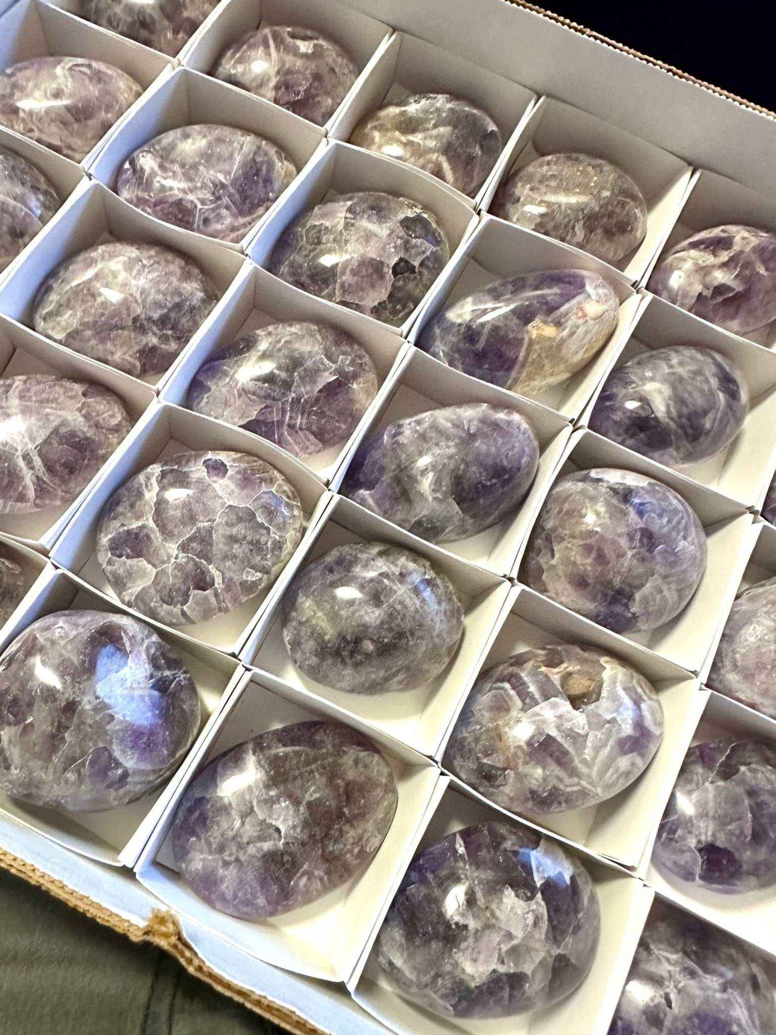 A polished amethyst palm stone showing its glassy violet surface.