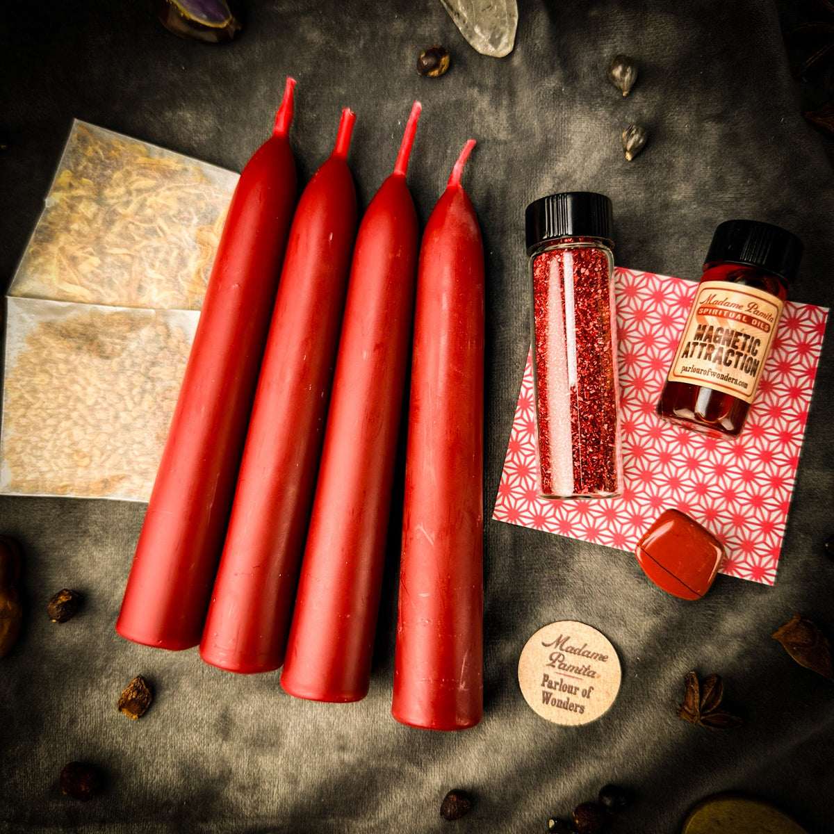 The same Attraction booster pack arranged on dark gray cloth under warm light, whole spices scattered around the edges.