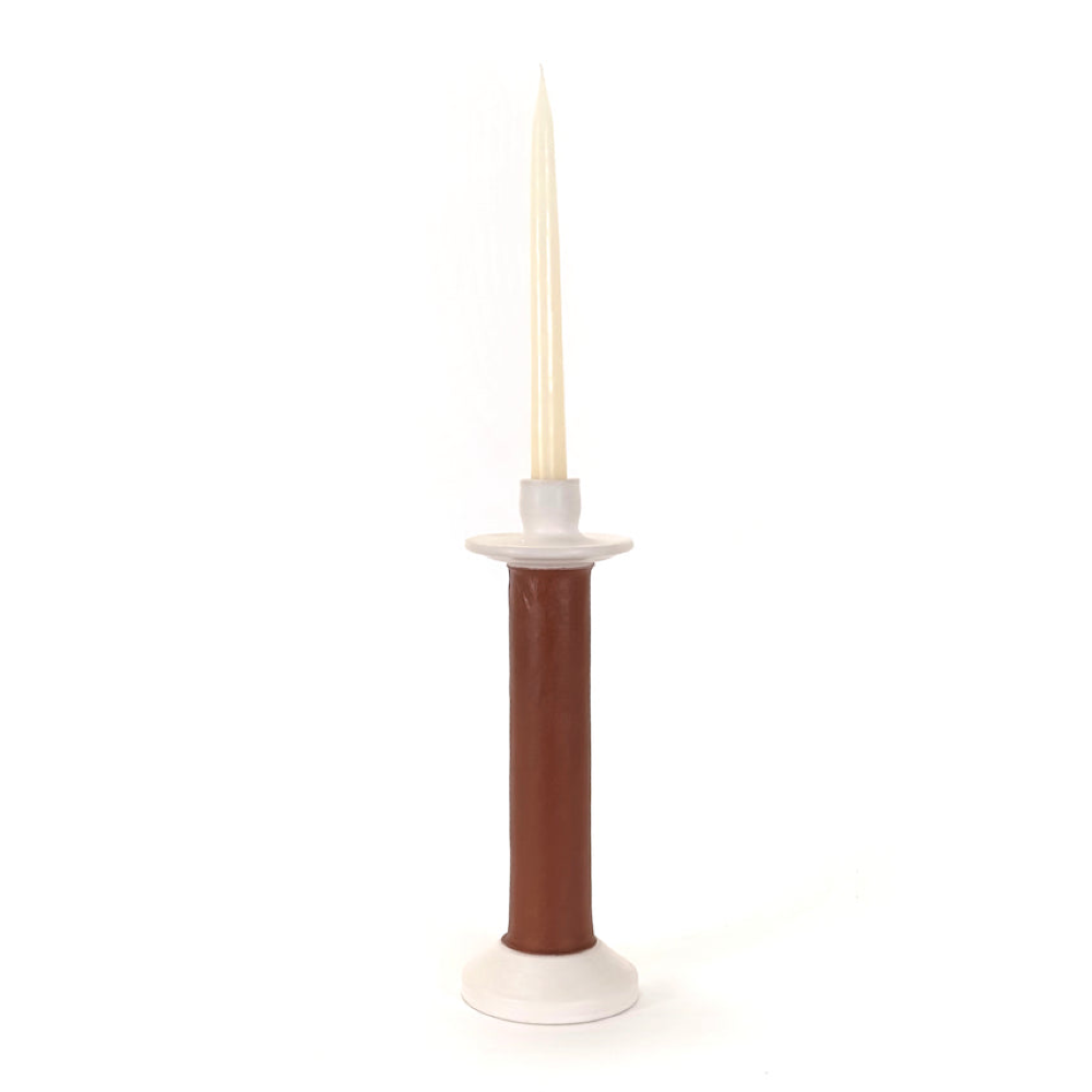 Brown leather-wrapped candle holder on a white ceramic base with a taper