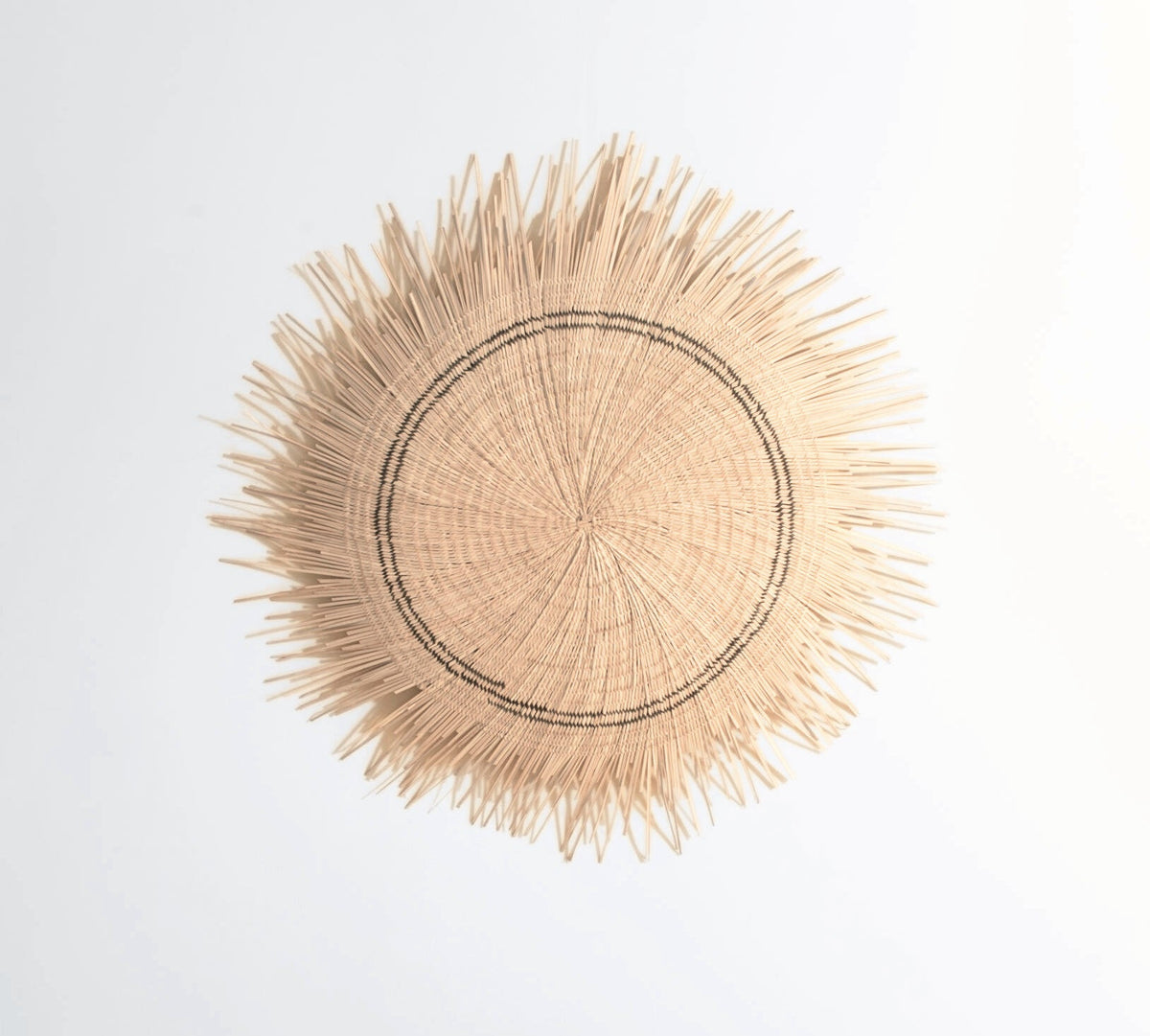 Sun Circle wall disc on white, showing the woven center and spiked edge