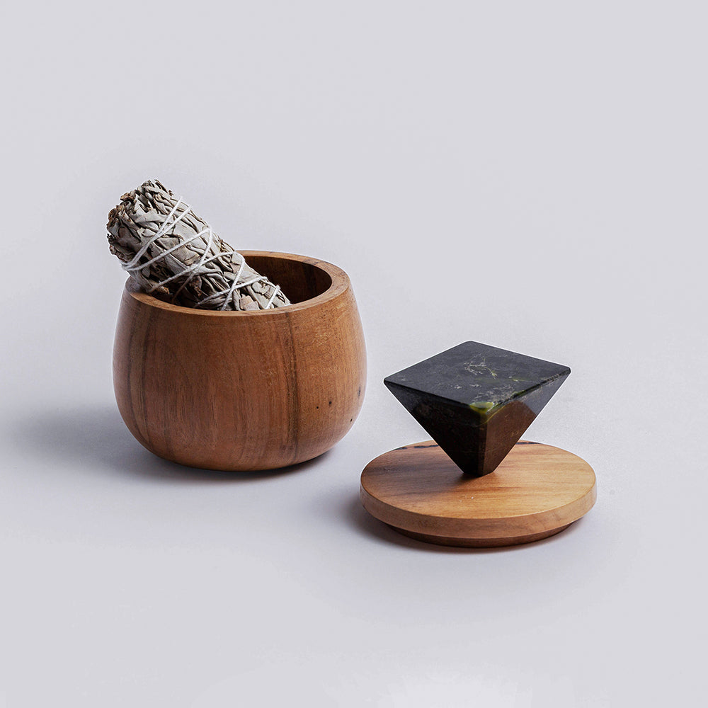 Round wood jewel box holding a sage bundle, lid beside it with the black onyx top