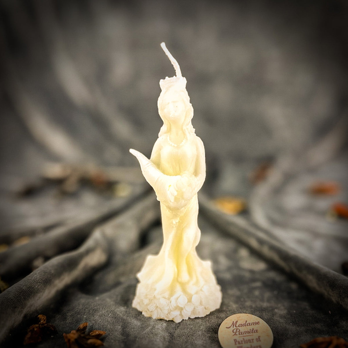 Fortuna Goddess of Luck beeswax candle in ivory white on draped gray fabric