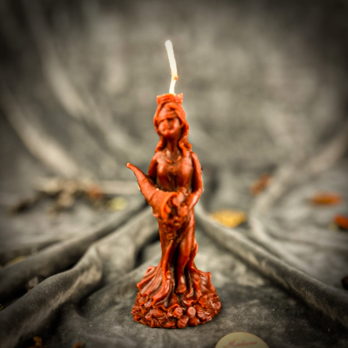 Fortuna Goddess of Luck beeswax candle in brown on draped gray fabric