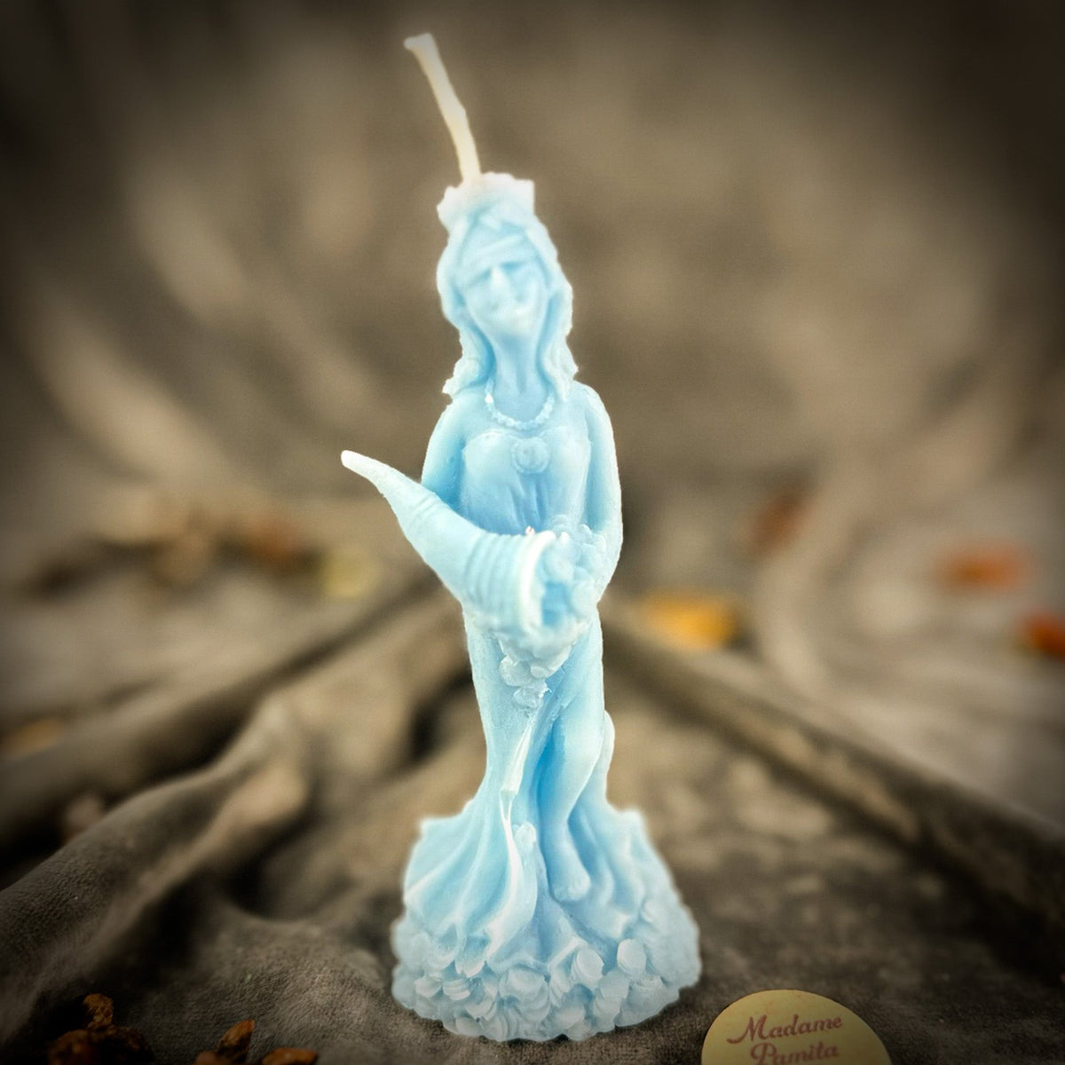 Fortuna Goddess of Luck beeswax candle in light blue on draped gray fabric