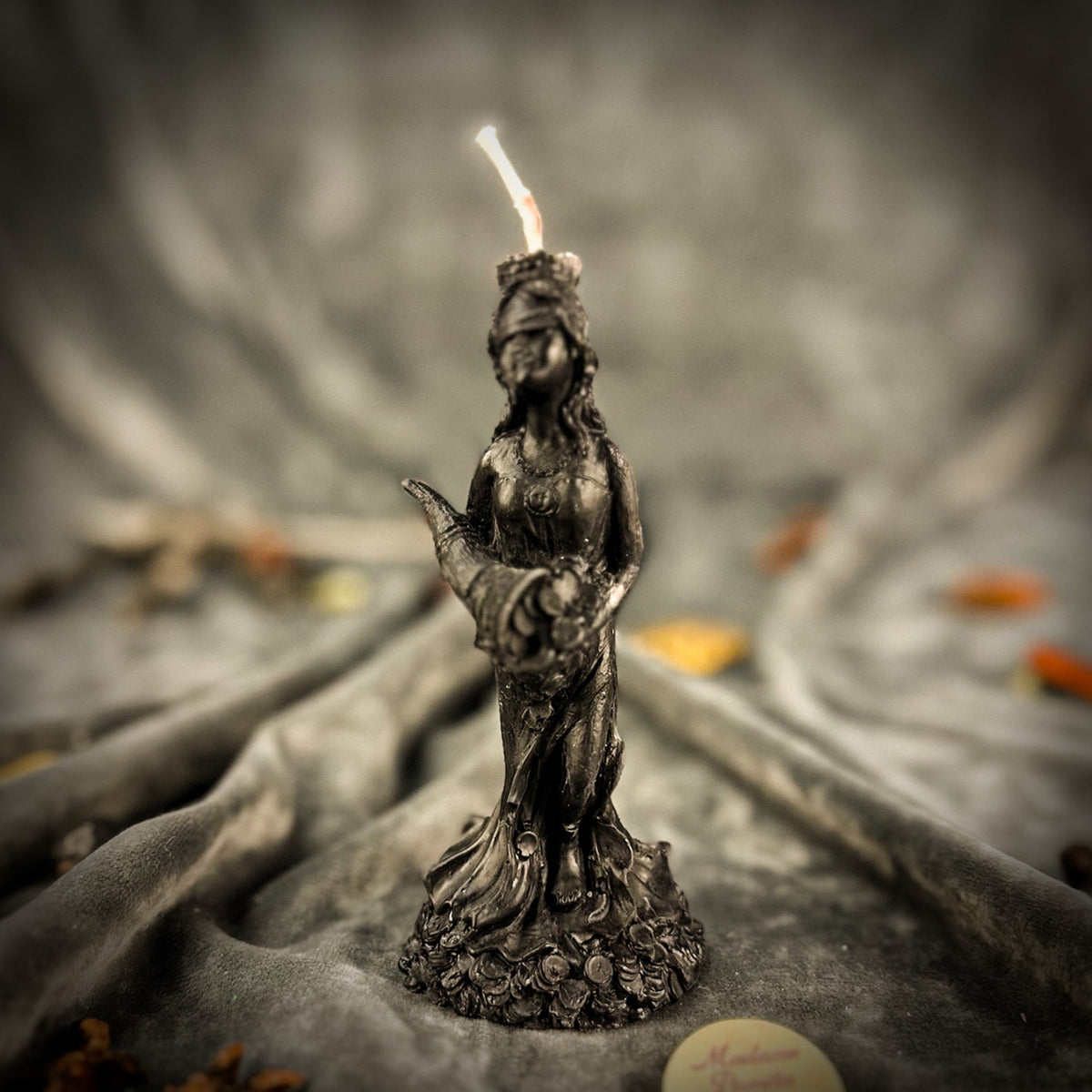 Fortuna Goddess of Luck beeswax candle in black on draped gray fabric