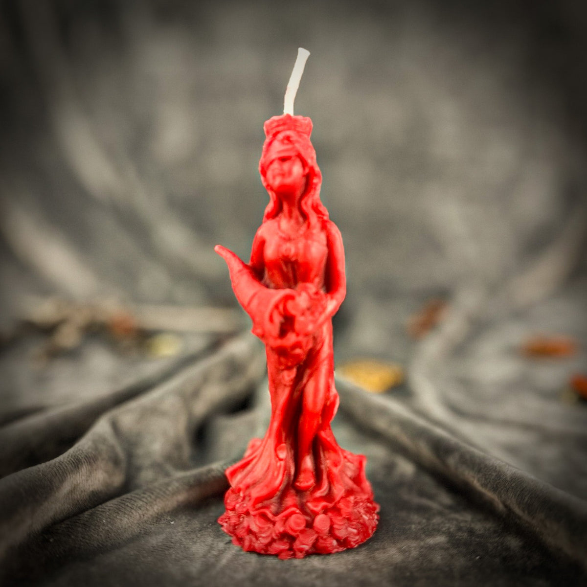 Fortuna Goddess of Luck beeswax candle in red on draped gray fabric