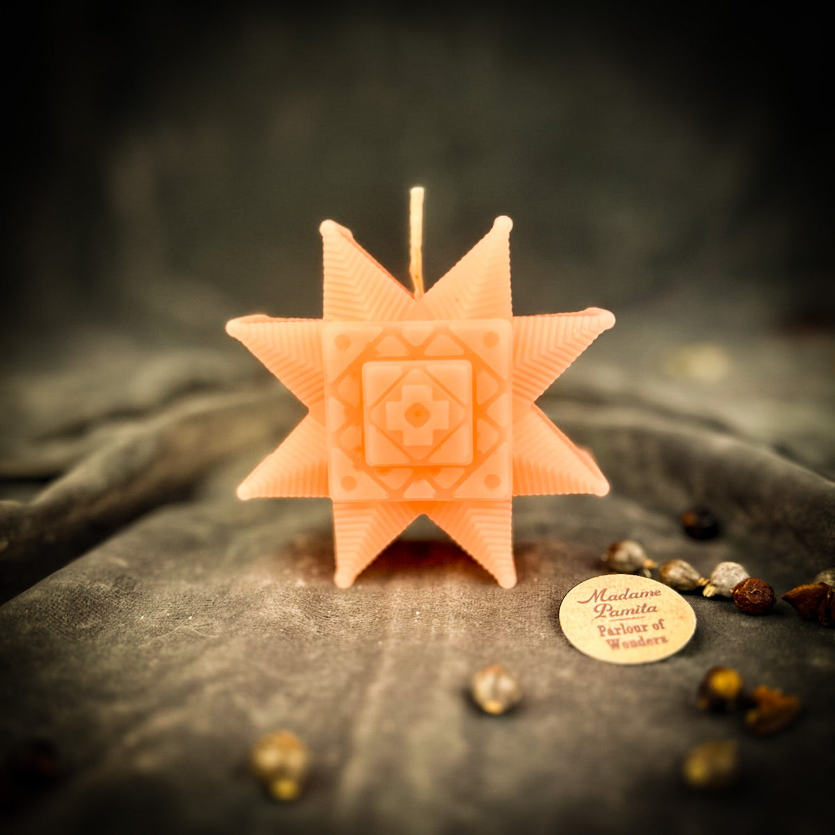 Peach Ruzha star candle standing on gray velvet