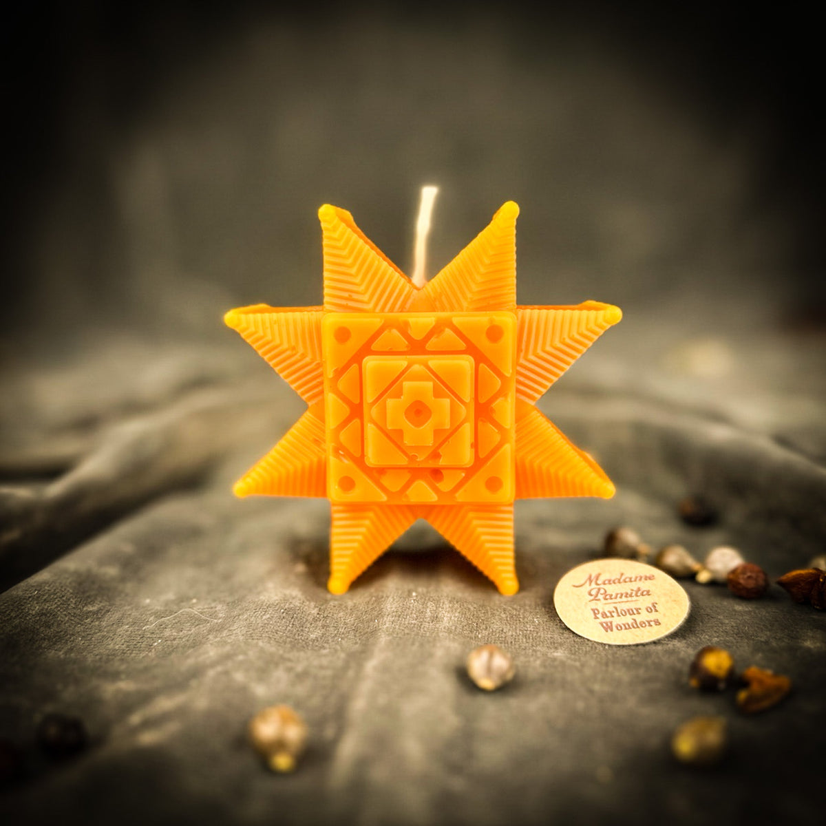 Orange Ruzha star candle standing on gray velvet