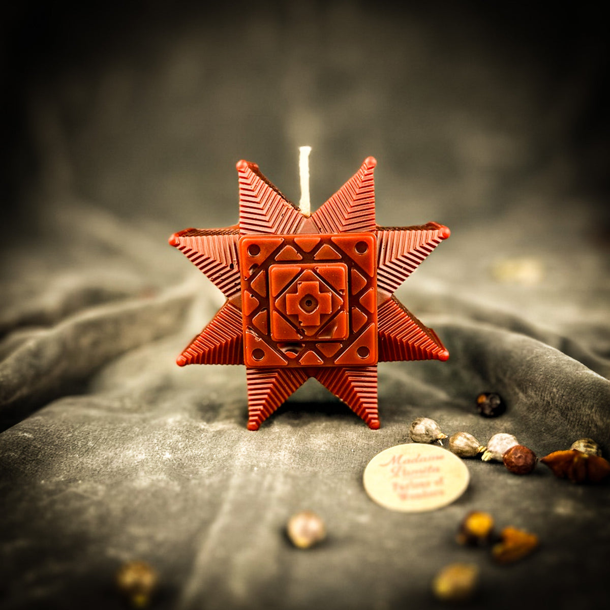 Rust-brown Ruzha star candle standing on gray velvet