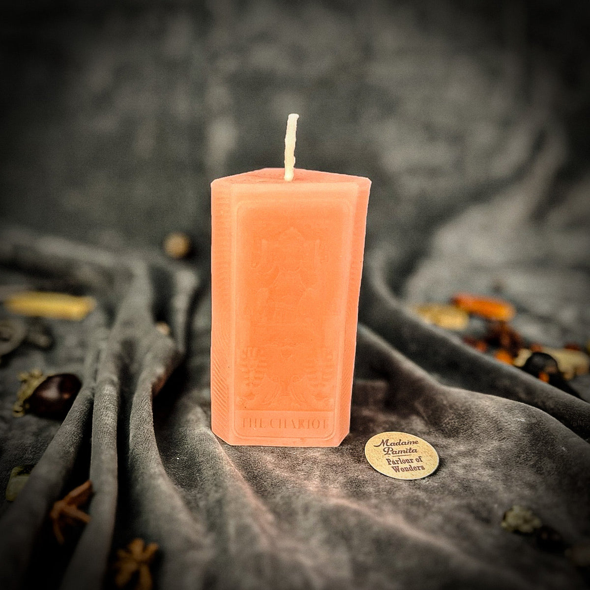Pale peach beeswax The Chariot tarot card candle on gray draped fabric