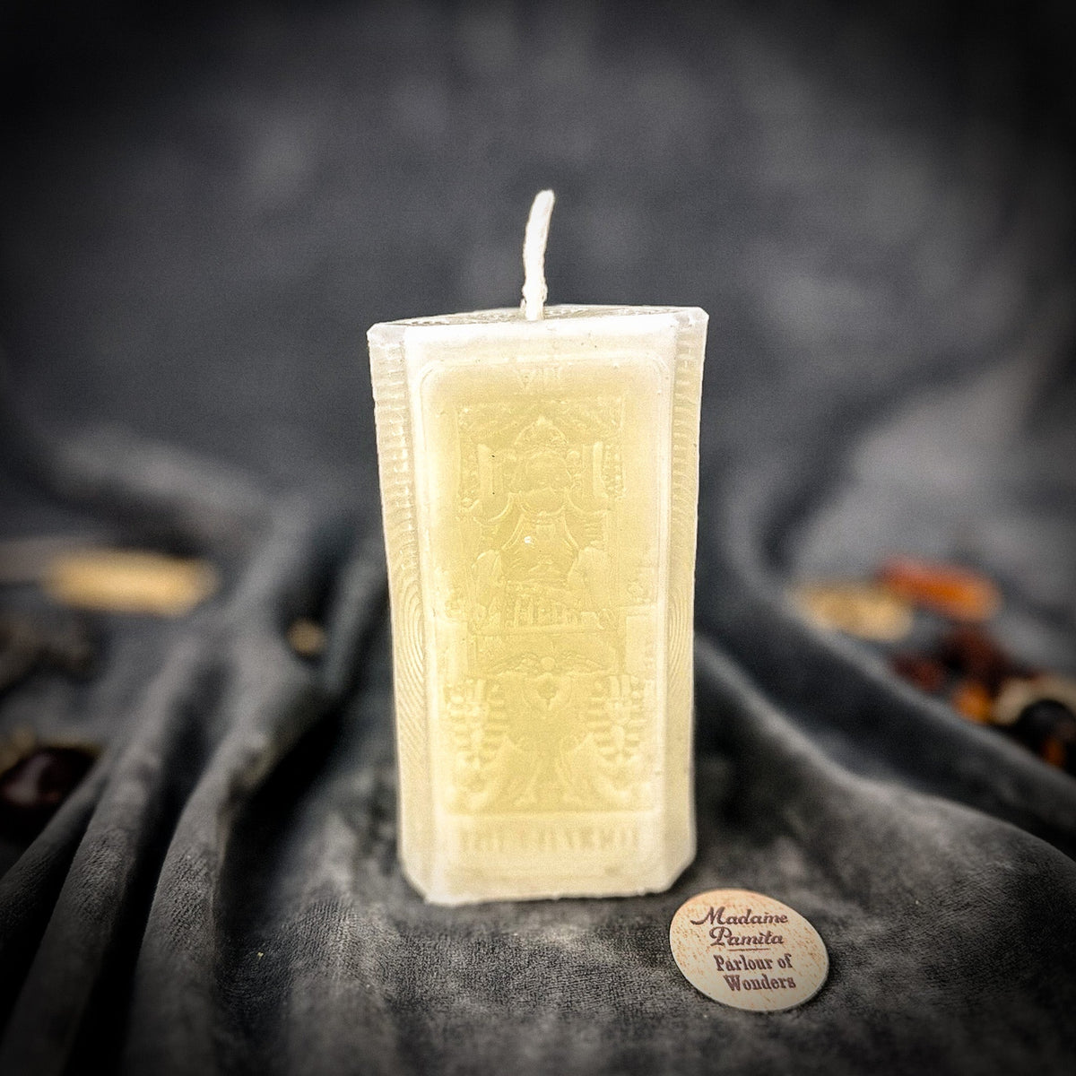 Cream white beeswax The Chariot tarot card candle against a dark gray background