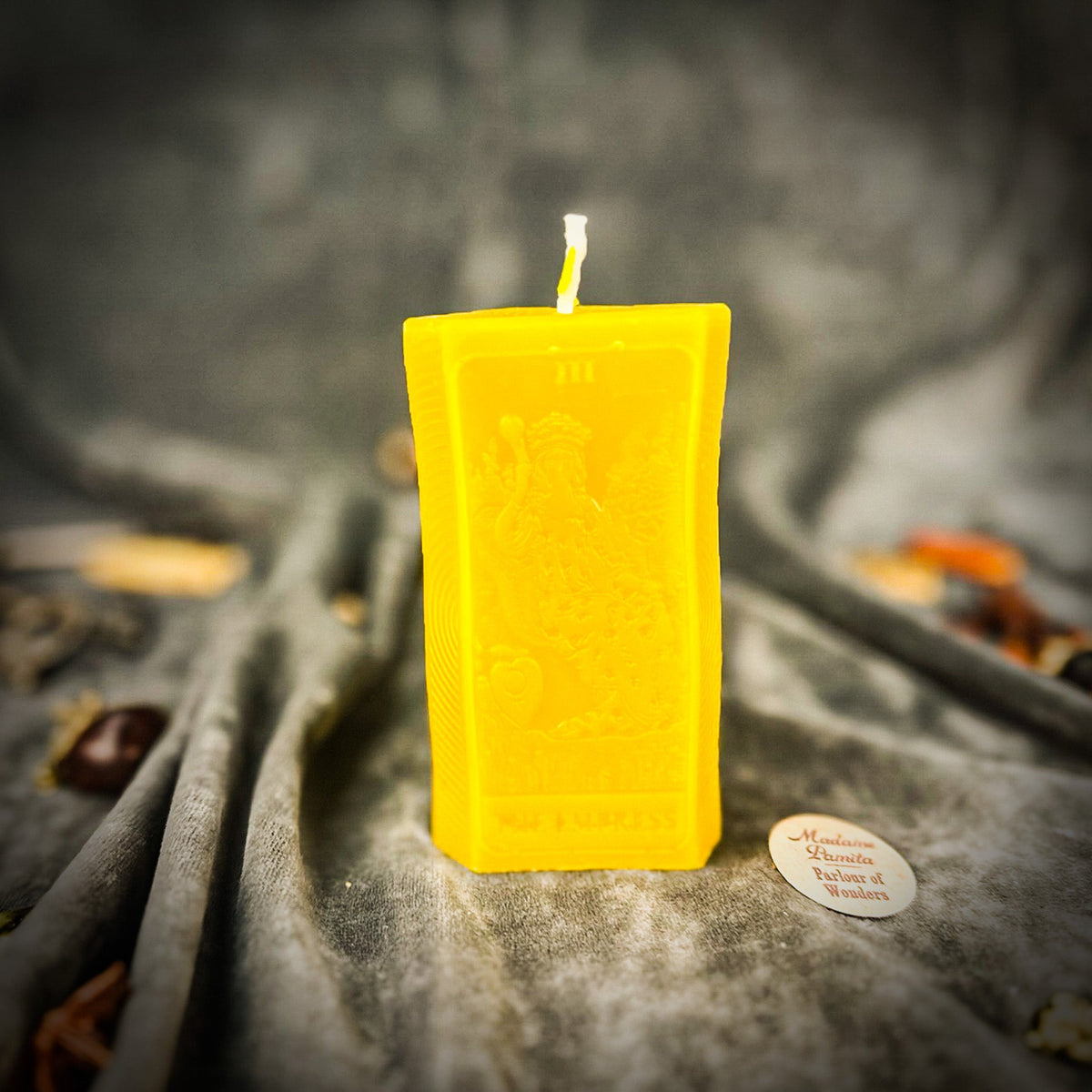 Golden yellow beeswax The Empress tarot card candle on gray cloth