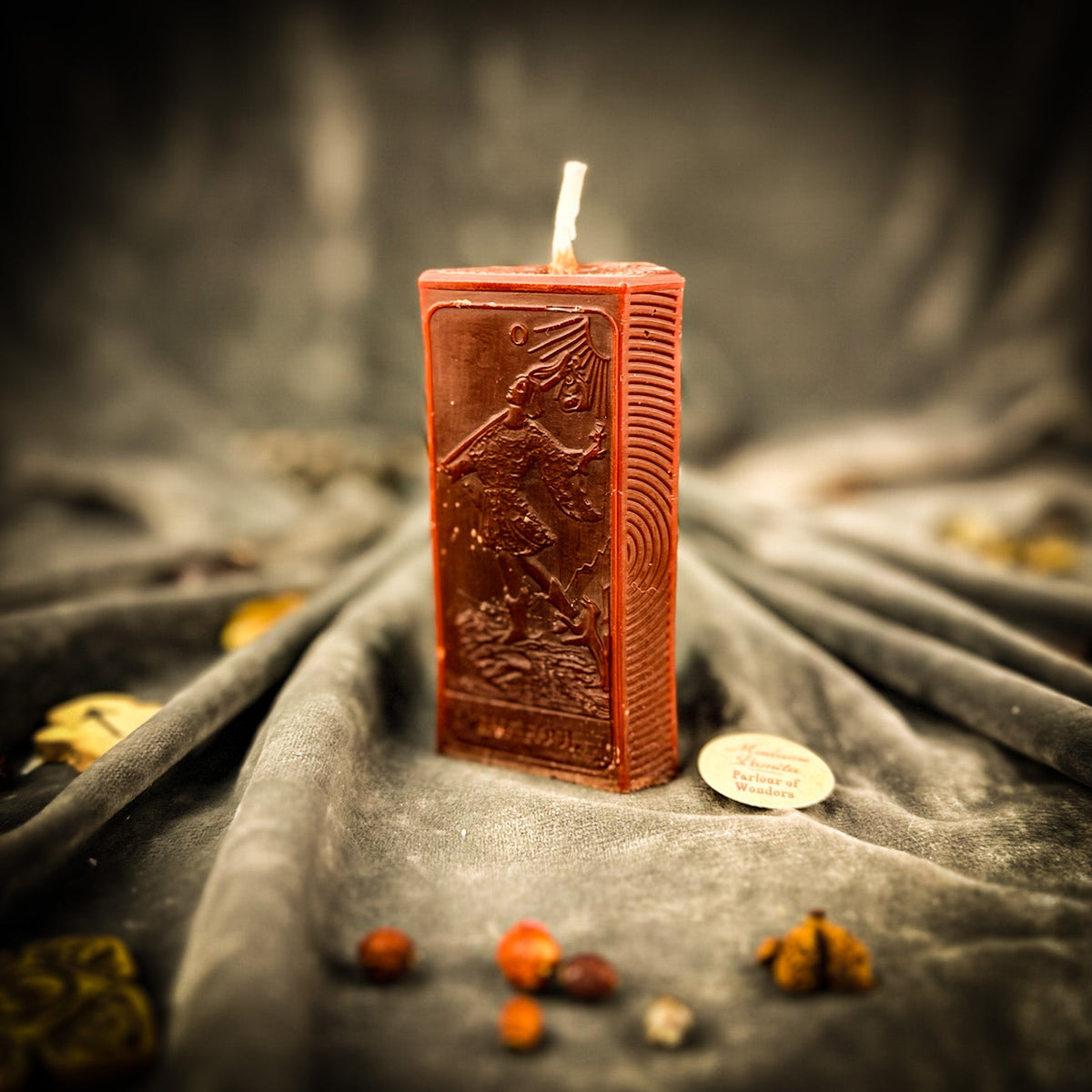 The Fool beeswax tarot candle in brown on draped gray fabric