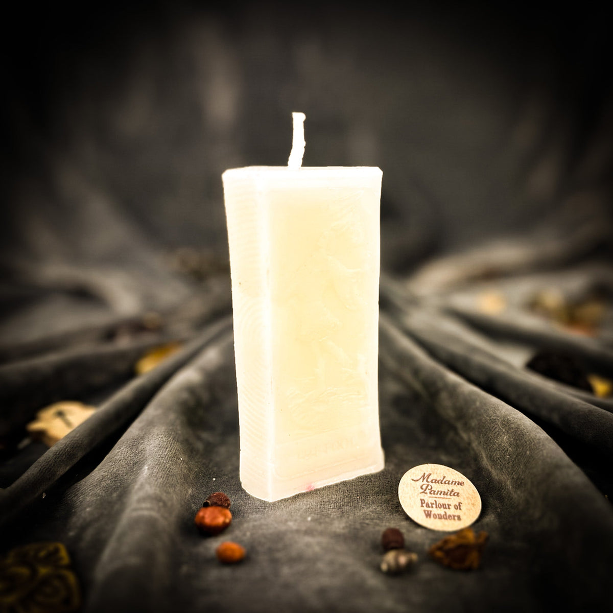 The Fool beeswax tarot candle in ivory white on draped gray fabric