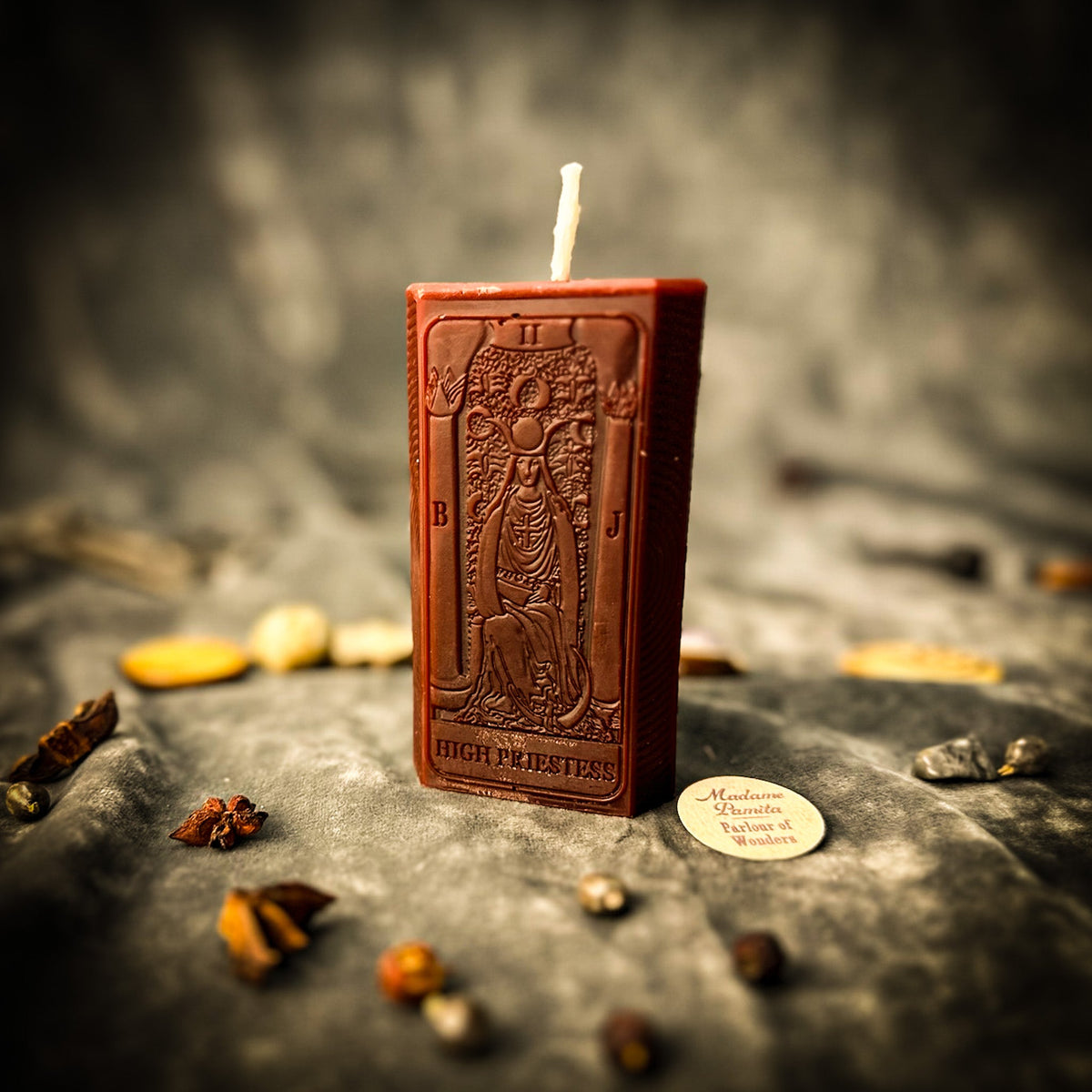 The High Priestess beeswax tarot candle in brown on draped gray fabric