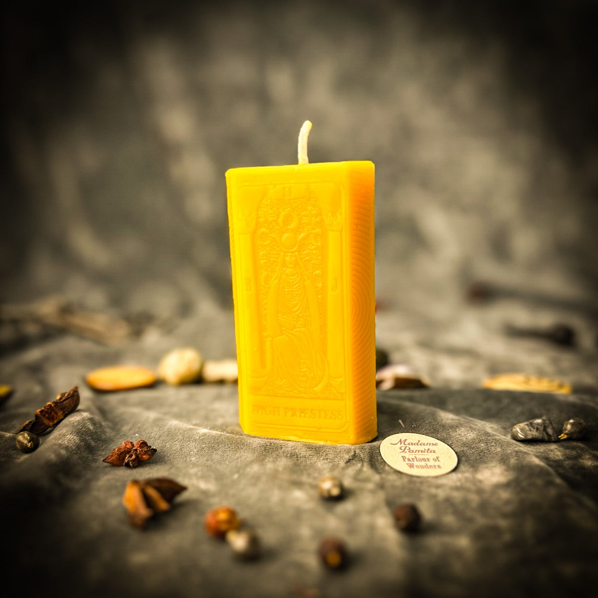 The High Priestess beeswax tarot candle in yellow on draped gray fabric