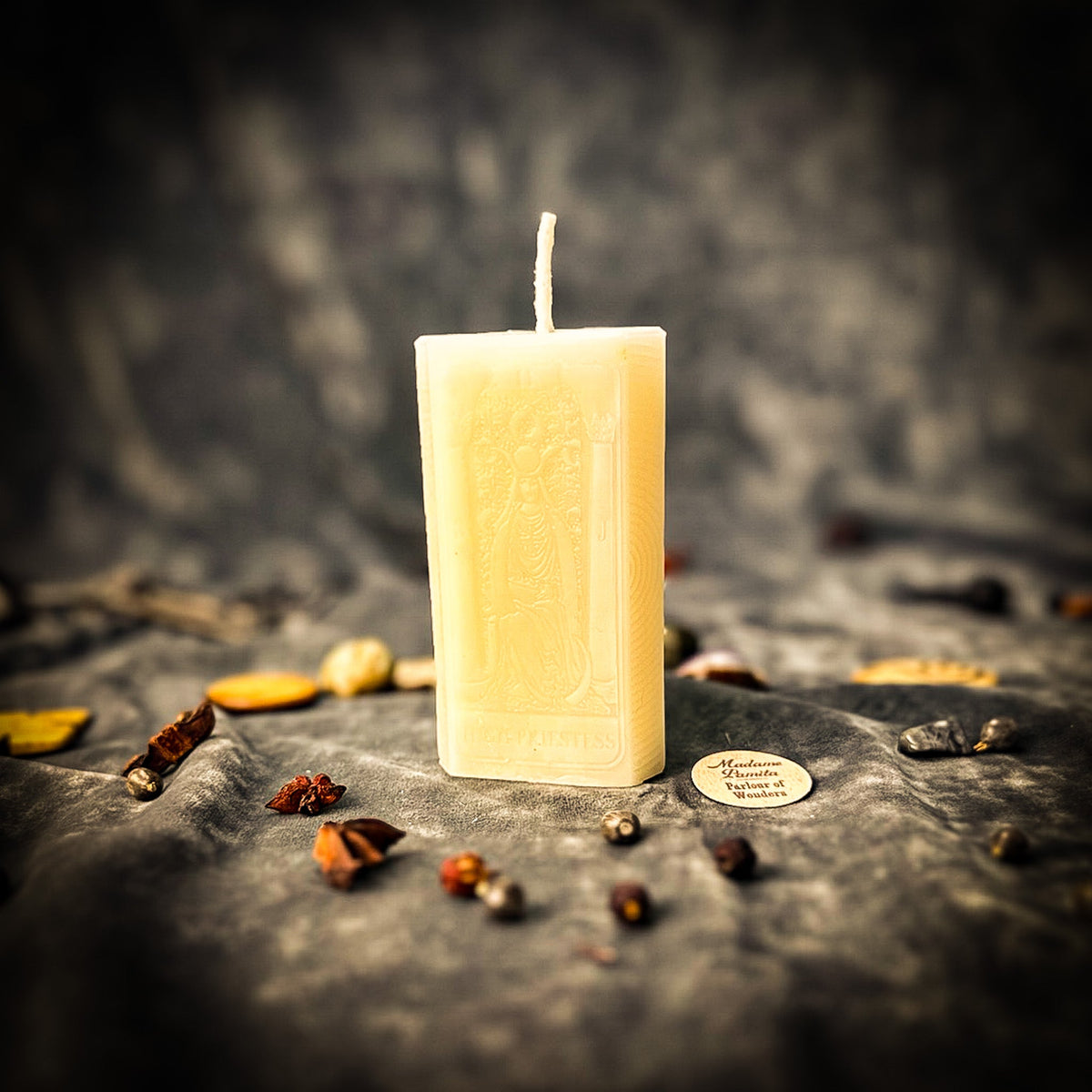 The High Priestess beeswax tarot candle in ivory white on draped gray fabric