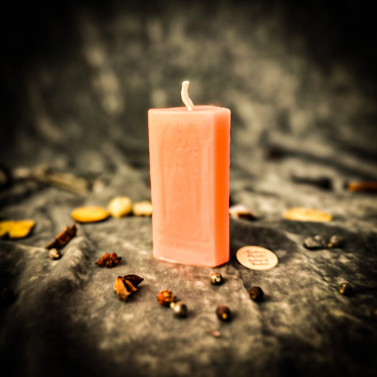 The High Priestess beeswax tarot candle in peach pink on draped gray fabric