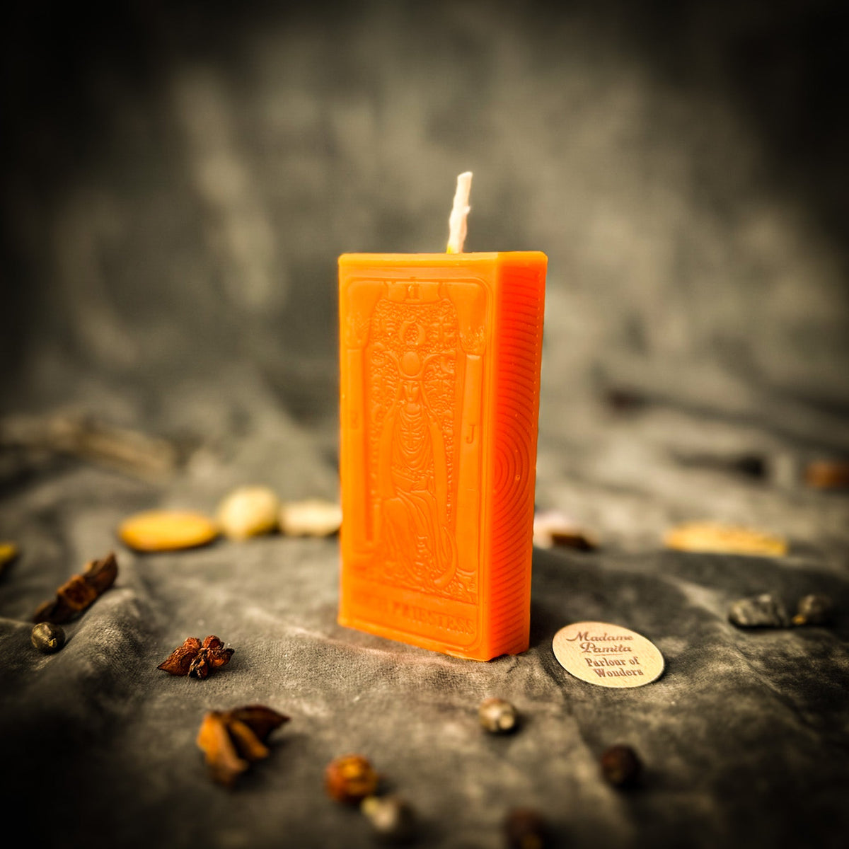 The High Priestess beeswax tarot candle in orange on draped gray fabric