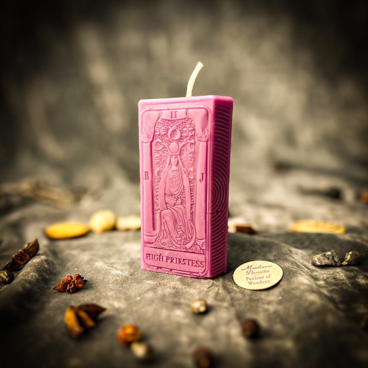 The High Priestess beeswax tarot candle in pink on draped gray fabric
