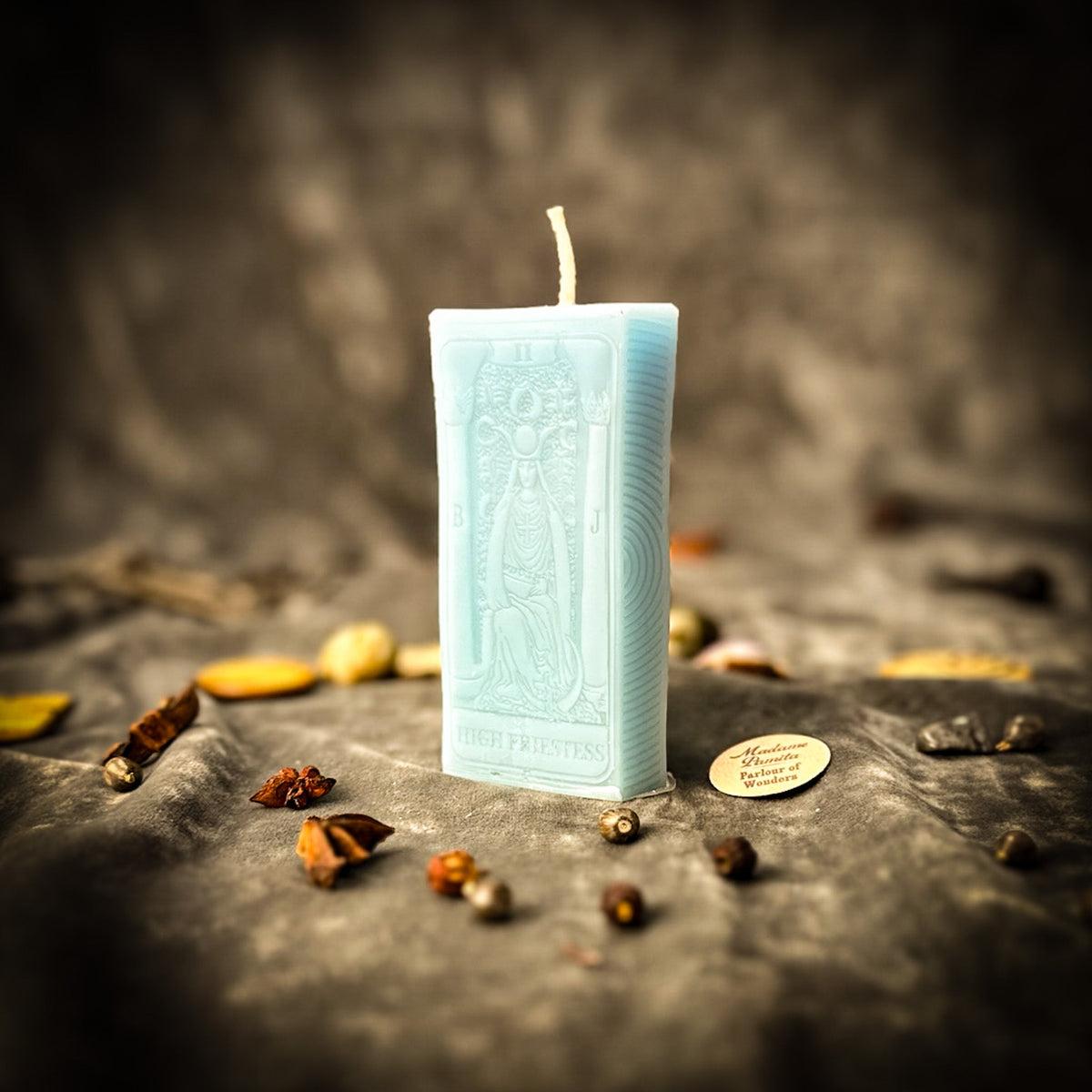 The High Priestess beeswax tarot candle in pale blue on draped gray fabric