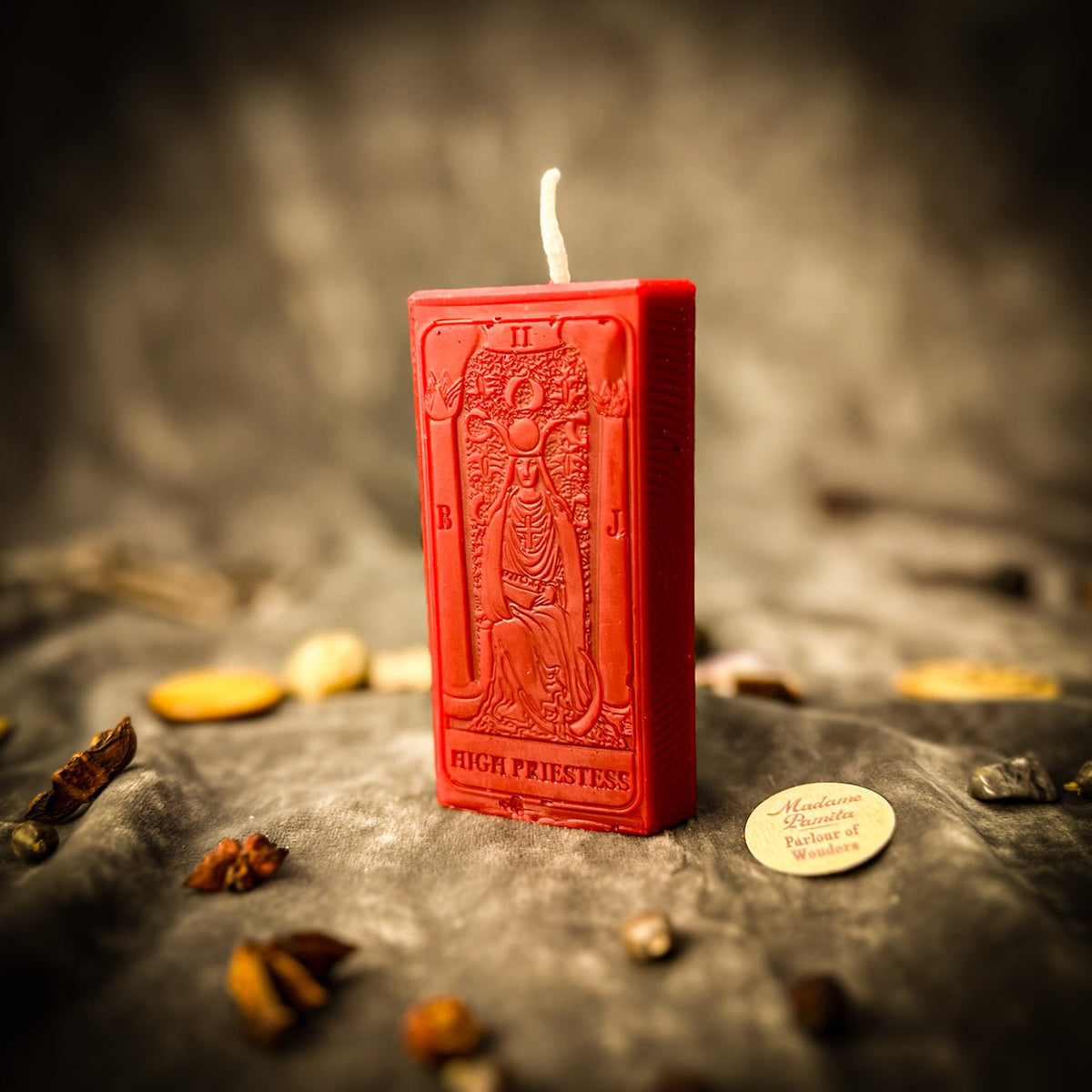 The High Priestess beeswax tarot candle in red on draped gray fabric