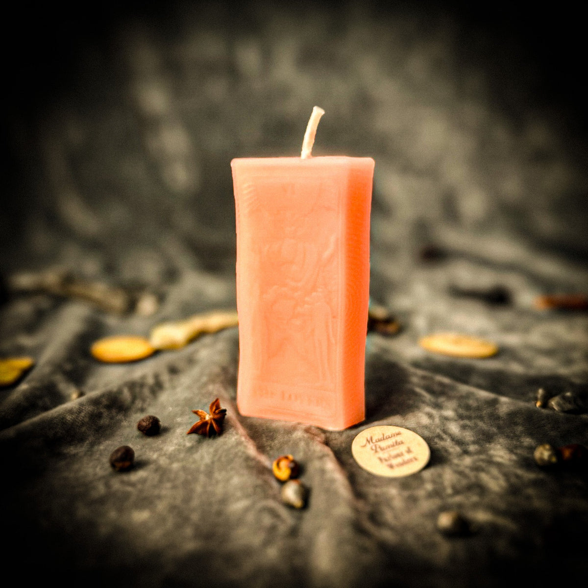 Pale peach beeswax The Lovers tarot card candle on gray draped cloth