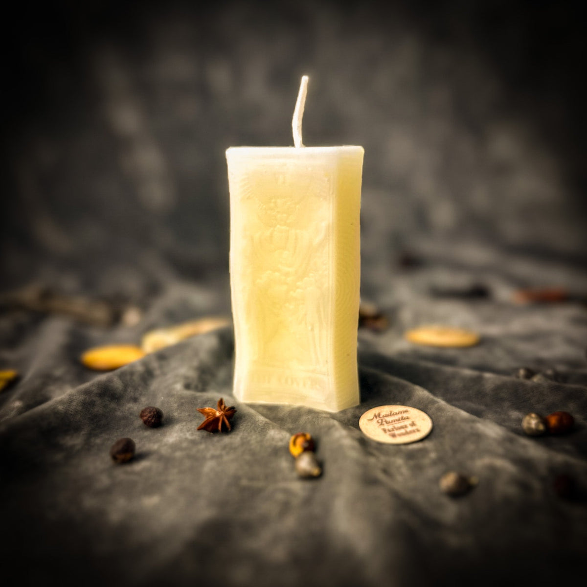 Cream white beeswax The Lovers tarot card candle standing on gray fabric