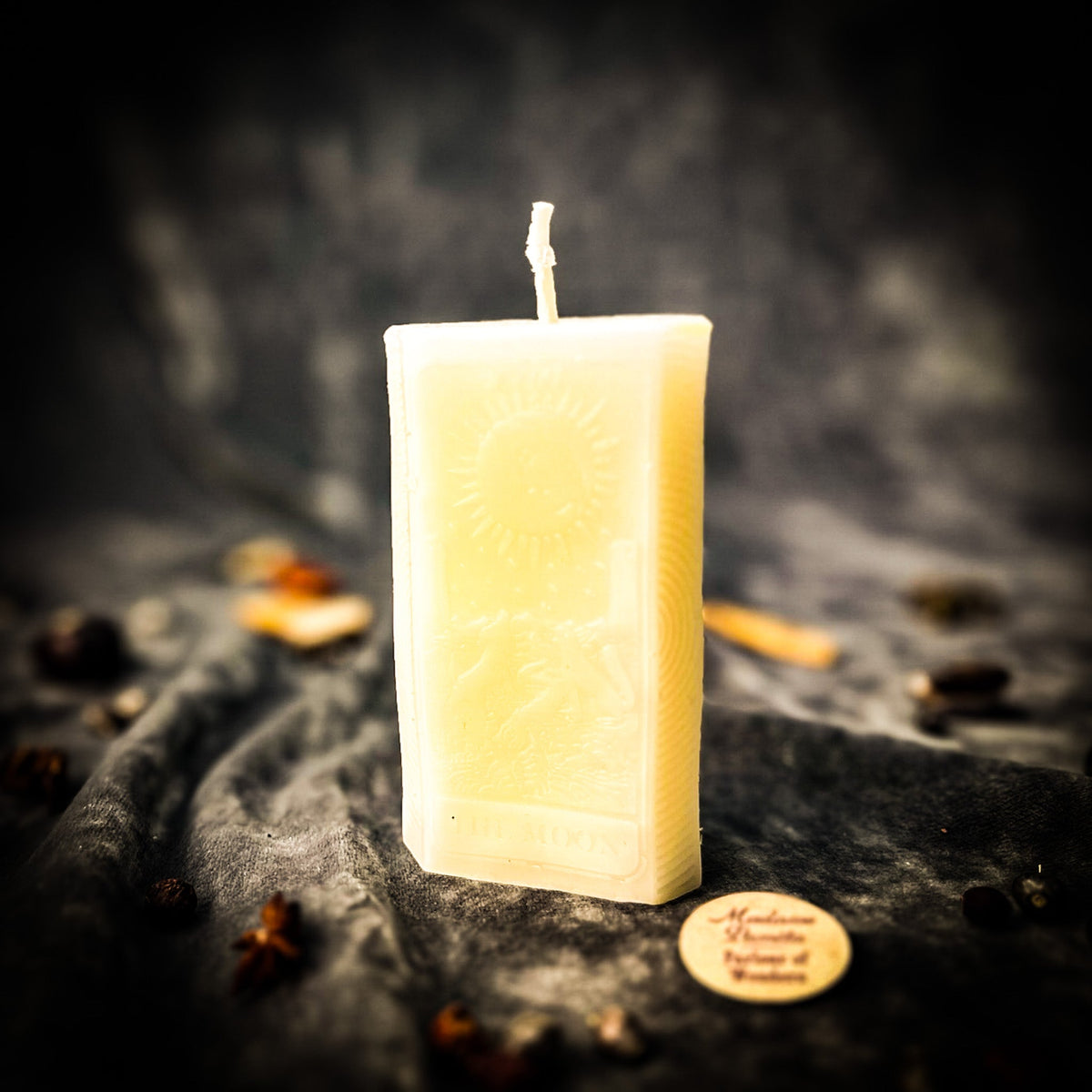 Cream white beeswax The Moon tarot card candle on gray fabric