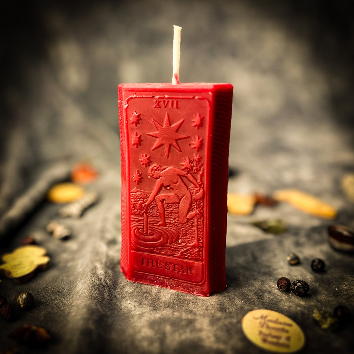 Deep red beeswax The Star tarot card candle, the relief design and the numeral XVII visible on its face