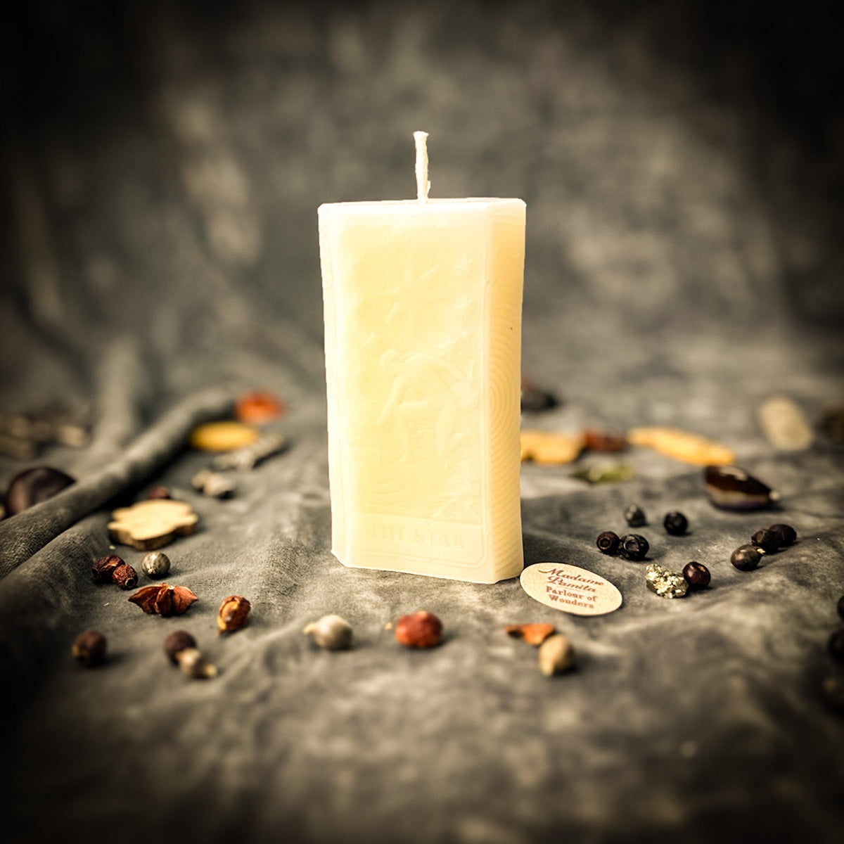 Cream white beeswax The Star tarot card candle on gray draped cloth