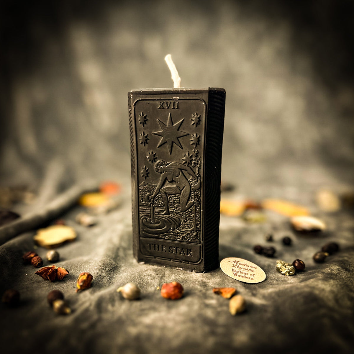 Black beeswax The Star tarot card candle, the embossed design catching the light