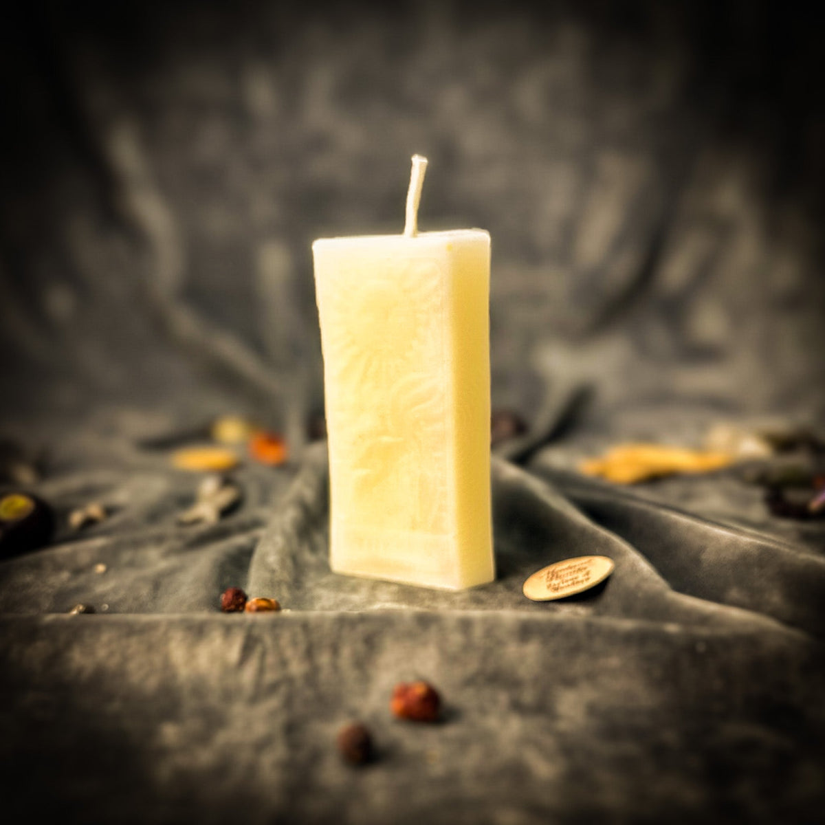 The Sun beeswax tarot candle in ivory white on draped gray fabric