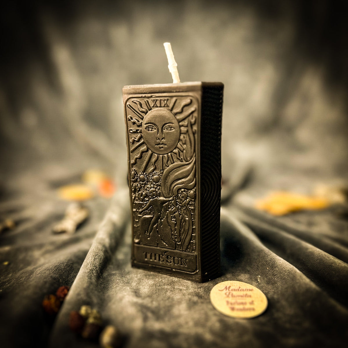 The Sun beeswax tarot candle in black on draped gray fabric