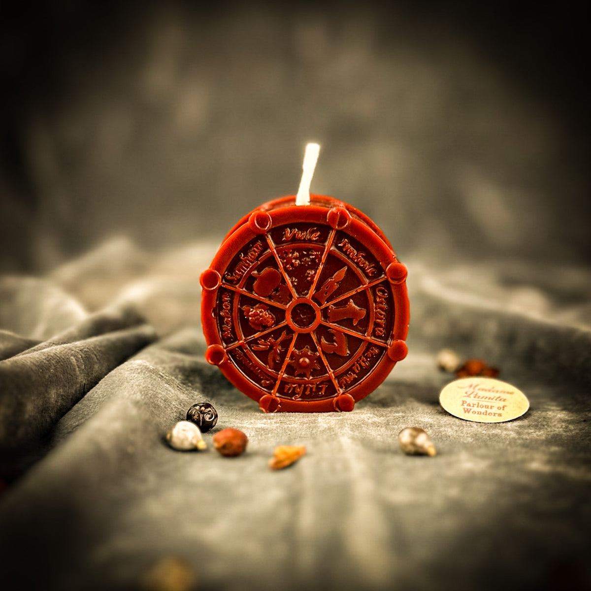 Red-brown Wheel of the Year candle on gray velvet.