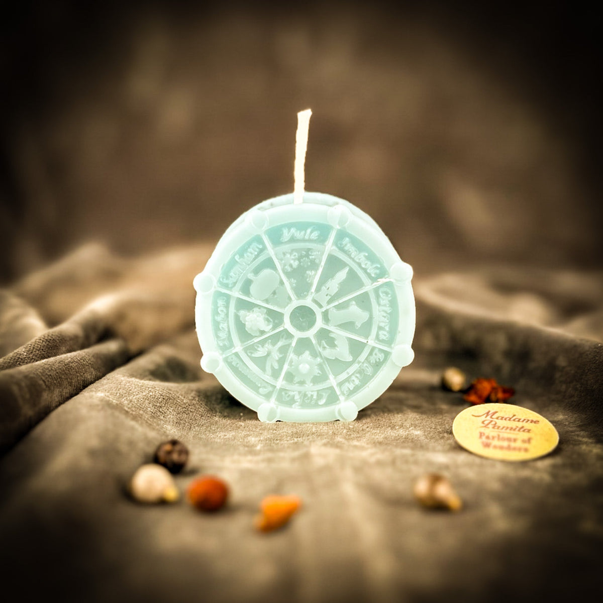 Pale mint Wheel of the Year candle, sabbat names legible around the outer ring.