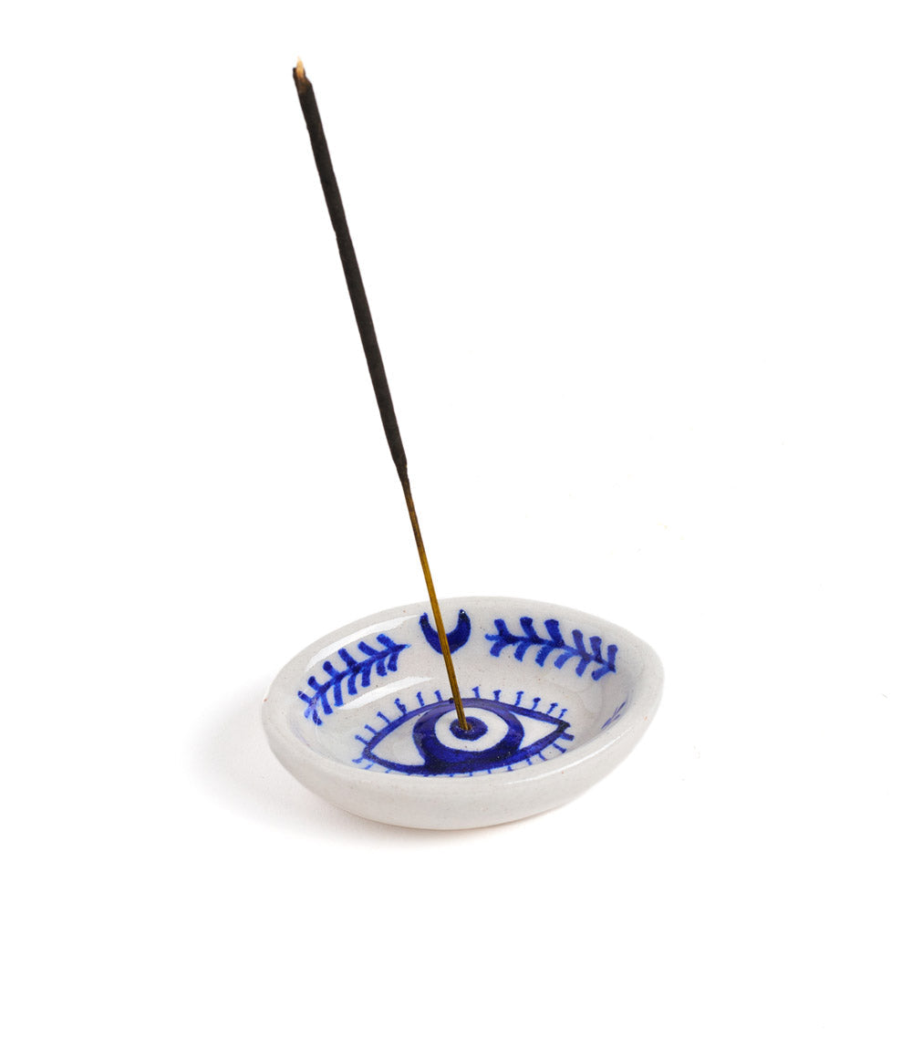 Evil eye ceramic incense holder with a stick set upright in the center hole