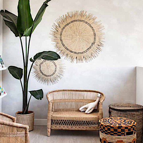 Two Sun Circle discs hung above a cane bench beside a large plant