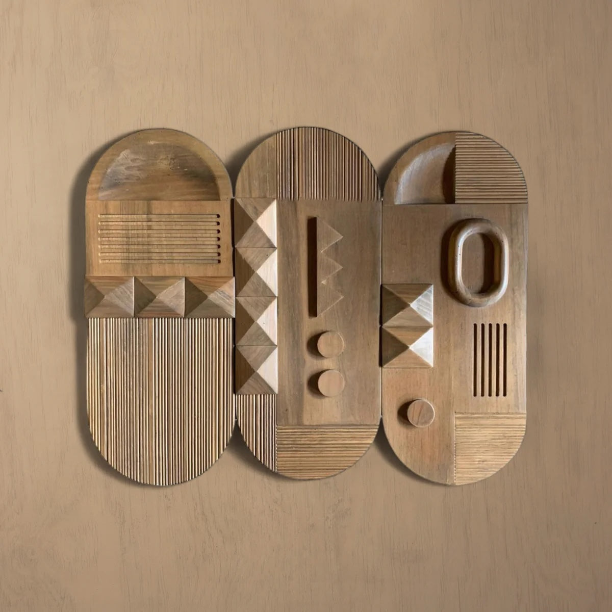 Three Planos wall panels hung together on a warm plaster wall, Planos I at the left