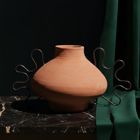 Ines terracotta vessel with wavy iron side handles on dark marble against green velvet