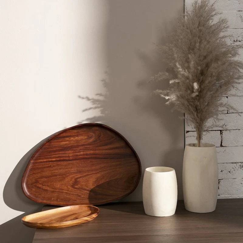 Wood leaf trays displayed upright and flat on a console beside a vase of dried grass