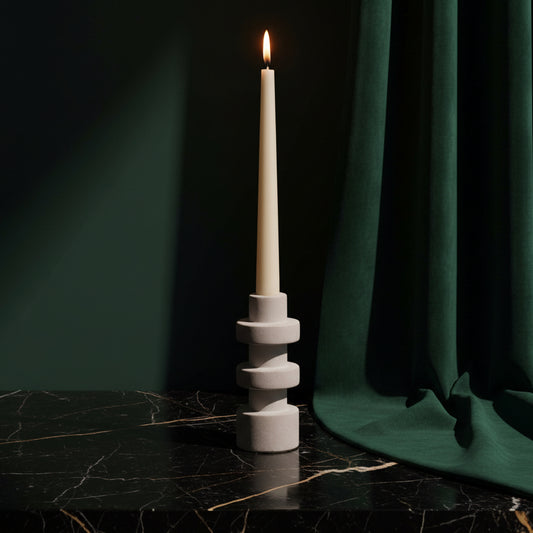 Pilar Tear sandstone holder with three offset tiers, holding a lit taper on black marble