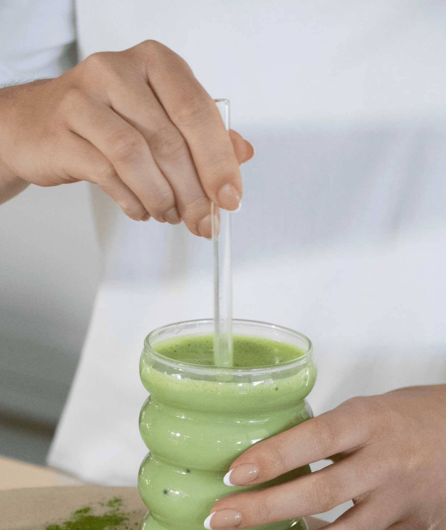 Glass straw resting in a tall glass of iced matcha latte